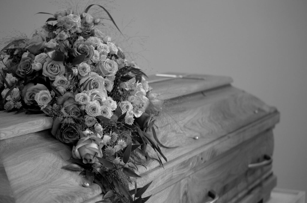 Beautiful black and white image of a casket adorned with roses, symbolizing peace and remembrance.